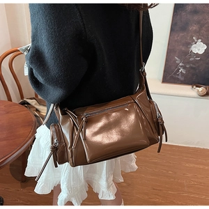 Gros plan du sac porté épaule en cuir vintage marron avec des poches zippées décoratives