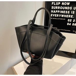 Detail of black pebbled leather tote bag with white contrast stitching and dual straps