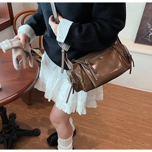 Détail du sac cylindre vintage en cuir PU marron brillant avec zips et longs pompons