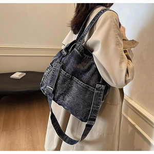 Detailed side view of dark grey washed denim tote bag with visible stitching and metal buckles