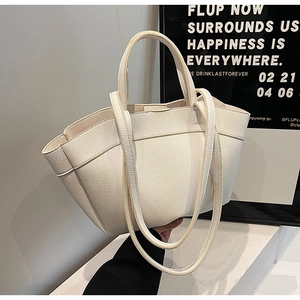Close-up of cream-colored tote bag in lychee pattern leather with dual circular handles
