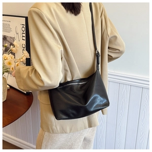 Detail of adjustable strap and zipper on minimalist black leather crossbody tote bag