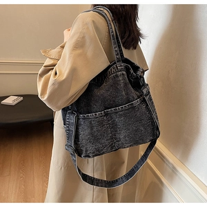 Black denim tote bag side view on female model wearing a long khaki trench coat