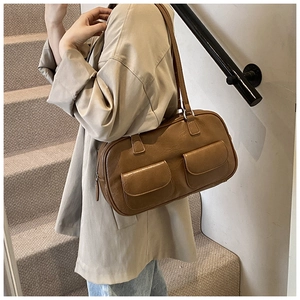 Detailed view of a vintage brown leather shoulder bag featuring two decorative front pockets
