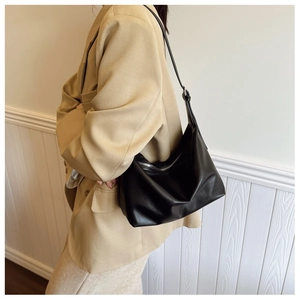 Detail of a large black faux leather tote with silver zipper and adjustable strap