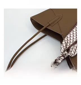 Détail du sac cabas en cuir marron grainé avec foulard à carreaux chic sur la poignée