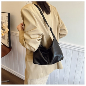 Detailed view of a black soft leather large tote bag on a model wearing a beige blazer
