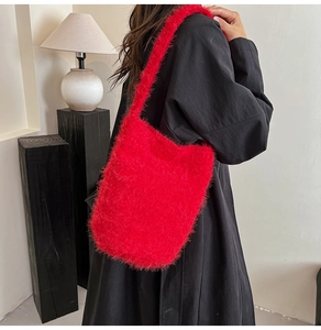 Close-up of red fuzzy plush shoulder bag with long hair texture on a black dress