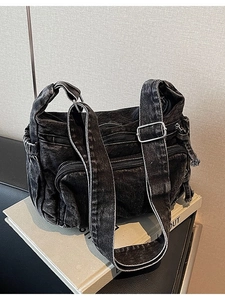 Distressed black denim crossbody bag with multiple pockets and wide adjustable strap