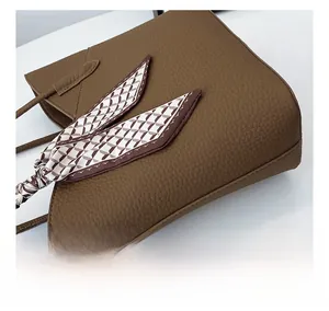Détail d'un sac cabas marron foncé en cuir grainé avec un foulard en soie décoratif