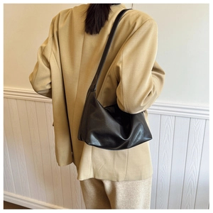 Minimalist black leather hobo bag with shoulder strap shown on a khaki blazer outfit