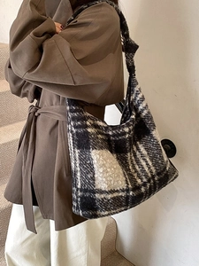 Large black and white checkered plush tote bag with wide shoulder strap on model