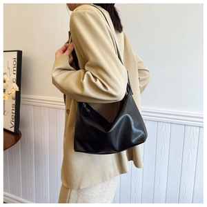 Detail view of the soft black leather hobo bag worn by a model in a modern room