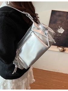 Sac à bandoulière argenté métallisé avec design multi-zipper présenté sur un mannequin