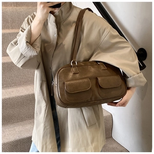 Detail view of dark coffee retro shoulder bag with dual front pockets on beige trench coat