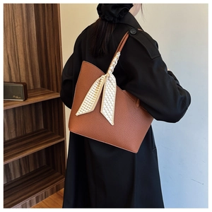 Détail du sac cabas marron motif litchi avec foulard en soie décoratif sur la poignée