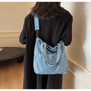 Rear view of model wearing a black coat with the light blue denim tote bag on the shoulder