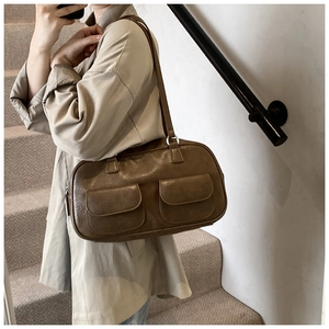 Detail of vintage dark brown shoulder bag featuring dual front pockets and silver ring hardware