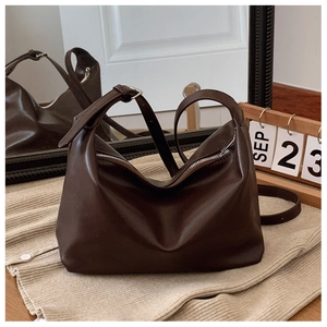 Detail of minimalist dark brown PU leather tote bag with metal zipper and adjustable strap