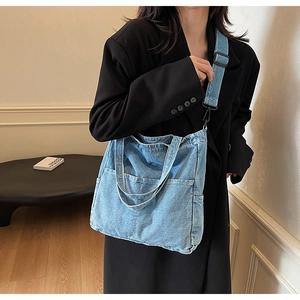 Detail of blue denim tote bag featuring dual front pockets and adjustable wide shoulder strap