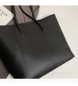 Close-up of minimalist black tote bag with smooth leather finish and fine curved stitching