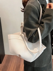 White leather tote bag with lychee texture shown on model in green corduroy suit