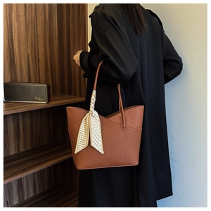 Sac cabas en cuir marron avec foulard en soie porté avec un manteau noir élégant