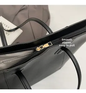 Close-up of smooth gold-tone zipper and herringbone lining on a black leather tote bag