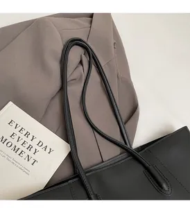 Close-up of the reinforced stitching and leather texture on a minimalist black tote bag