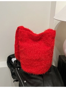 Plush red faux fur bucket bag shown on a black leather jacket for autumn style
