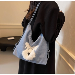 Model wearing a light blue denim tote bag with a white plush dog embroidery detail