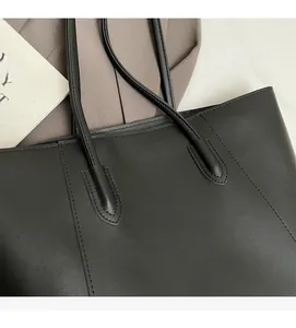Detail shot of black leather tote bag showing high-quality stitching and matte texture