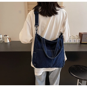 Detail of dark blue denim tote bag with visible stitching and adjustable strap