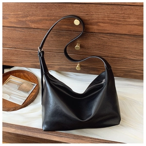 Detail of minimalist black matte leather hobo bag on elegant silk background