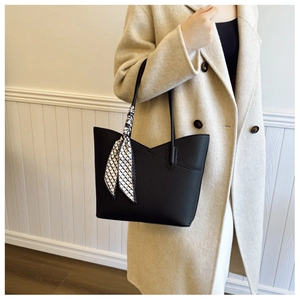 Détail du sac cabas noir texture litchi avec un foulard géométrique élégant au manche