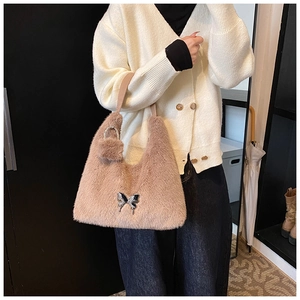 Detailed view of brown faux fur hobo bag with silver butterfly buckle and fur pompom