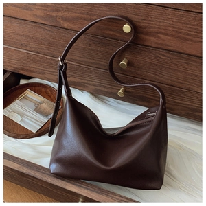 Close-up of a dark brown soft leather tote bag inside a vintage wooden drawer