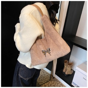Detail of plush faux fur shoulder bag featuring a metallic bow and brown leather strap