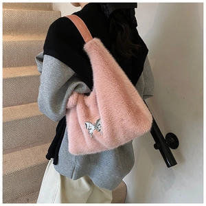 Detailed texture of pink faux fur shoulder bag featuring a silver metal butterfly charm