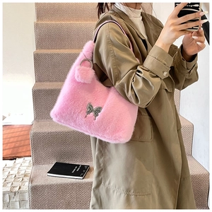 Close-up of pink faux fur shoulder bag with silver butterfly charm and plush pompom detail