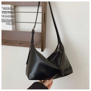 Close-up of a black minimalist hobo bag featuring a silver zipper and smooth leather texture