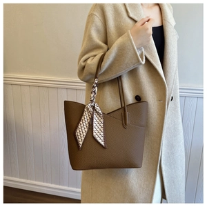 Détail du cabas en cuir grainé marron foncé avec foulard en soie géométrique sur la bandoulière