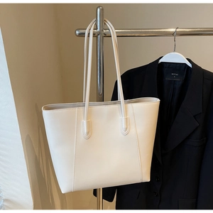 Close-up of minimalist white leather tote bag with grainy texture and slender straps