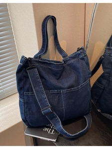 Large dark blue denim tote bag with front pockets and adjustable strap for daily use