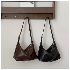 Detail of crescent leather shoulder bags in black and brown hanging on wooden hooks
