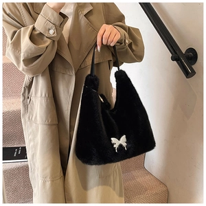 Close-up of black faux fur handbag with silver butterfly ornament on stylish handle