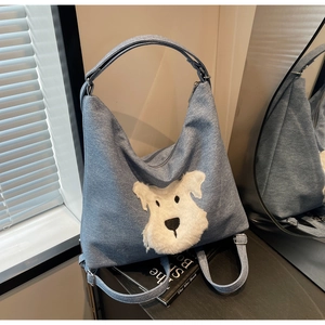 Detail of light blue denim tote bag with white plush schnauzer embroidery in a bright room
