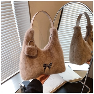 Detail of plush faux fur shoulder bag with butterfly metal logo and soft textures