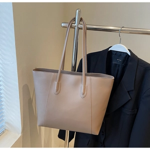 Detailed close-up of khaki tote bag texture and long shoulder straps on a metal rack