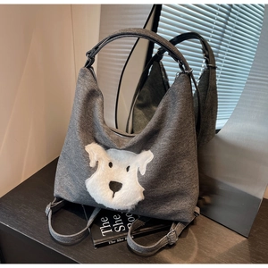 Detail of grey denim tote bag with 3D plush puppy patch and adjustable fabric strap